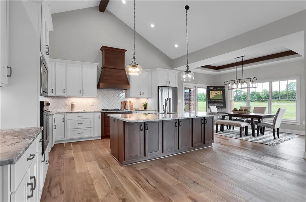 Open kitchen and dining rom with wooden floors, granite counter tops, and silver appliances designed and created by Dave Sego Builders, Inc. in Greenfield, IN